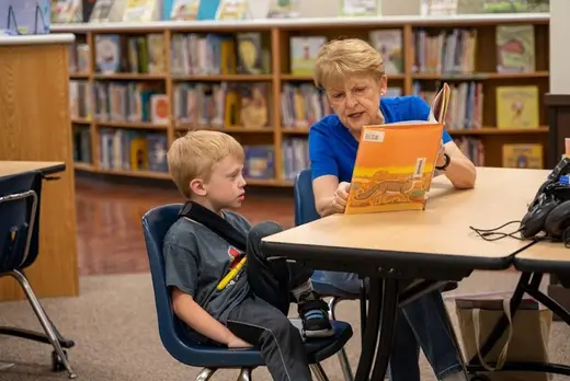 Elderly woman reading to child in library at Under Angel's Wings Recovery Center LLC, treatment center in Bronx.